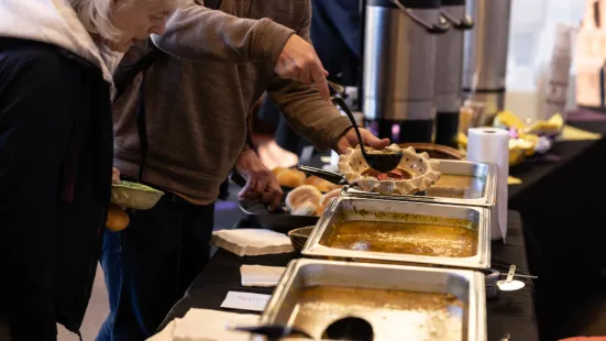 A close-up of people serving themselves soup from a buffet