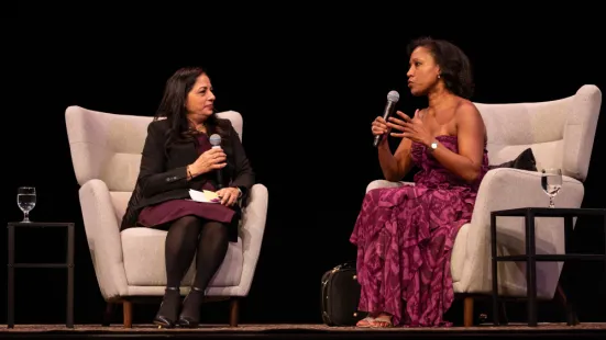 Anupama Pasricha, PhD, and Kelly Hall-Tompkins sit in chairs onstage during a Q&A