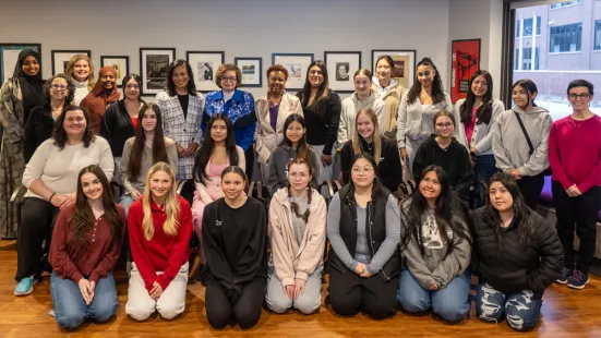 Three rows of people, both kneeling and standing, smile and pose.