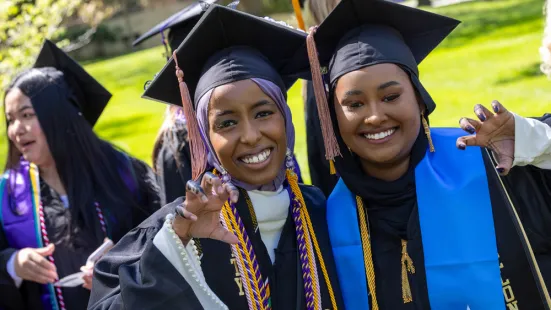 Two graduates wearing caps and gowns smile.