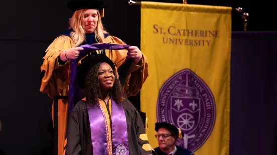 A faculty member places a stole around the shoulders of a graduate