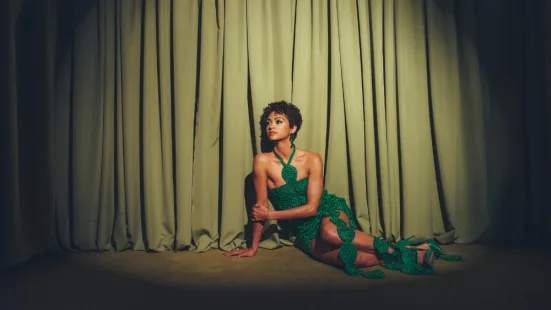black woman with short hair sitting down in a green dress