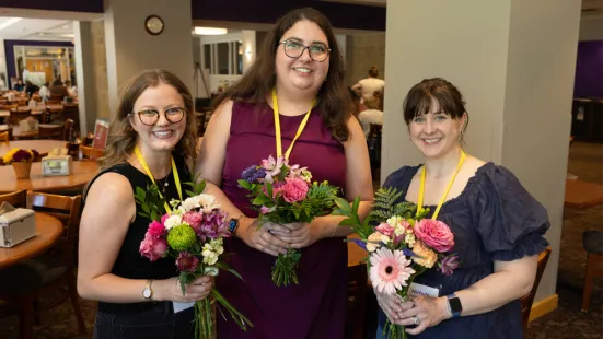 Three alums hold bouquets of flowers from the flower arranging workshop.