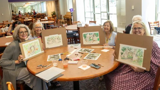 A group of women hold up their paintings at the Sip and Paint during Reunion.