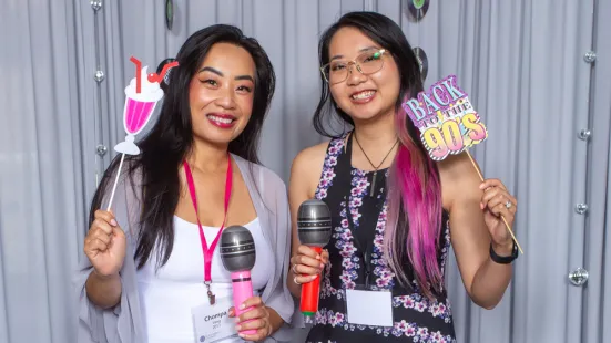 Two alums pose with prop microphones and signs at Reunion.