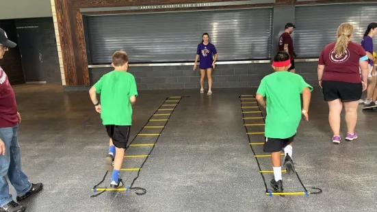 Kids run drills through a ladder during the STEM clinic.