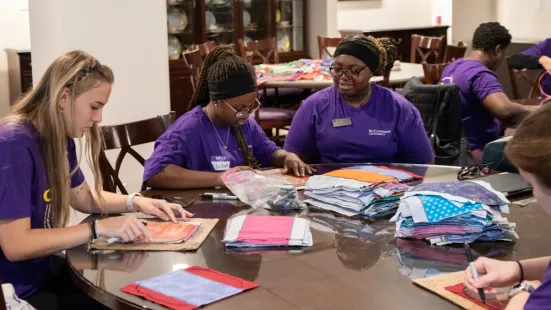 Volunteers work at a table with stacks of fabric. 