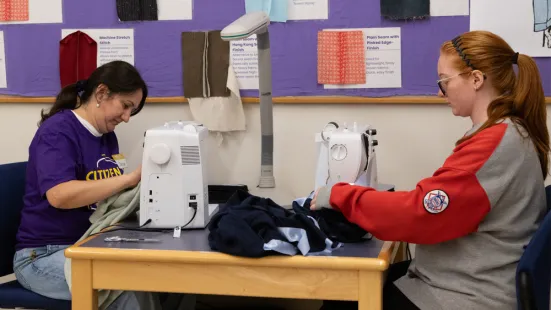 Two volunteers work on sewing machines. 