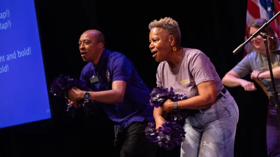 President Evans holds pom-poms as part of a cheer on stage.