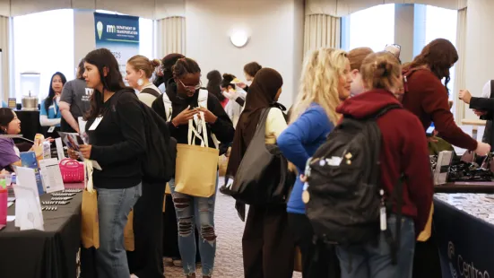 Students gather in groups around tables at the career fair.