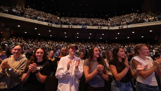 Students in the front row of the O'Shaughnessy auditorium stand and clap.