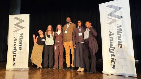 A group of five St. Kate's students and their supervisor, Ibrahim Soumare, gather on stage to celebrate a team win at the student data challenge by MinneAnalytics.