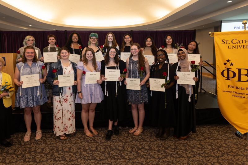 New inductees pose next to the Phi Beta Kappa banner. 
