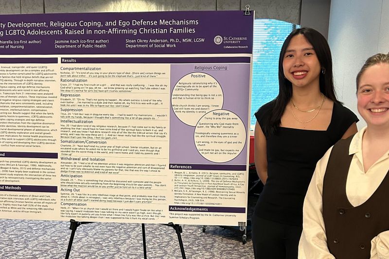 Two students stand next to their Summer Scholars research poster