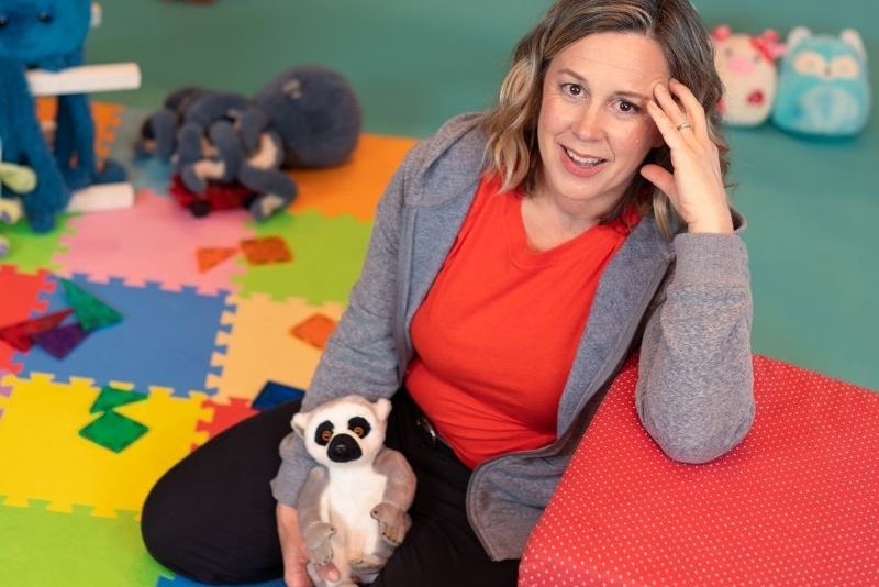Woman sitting in a childrens playroom with her arm on a red block
