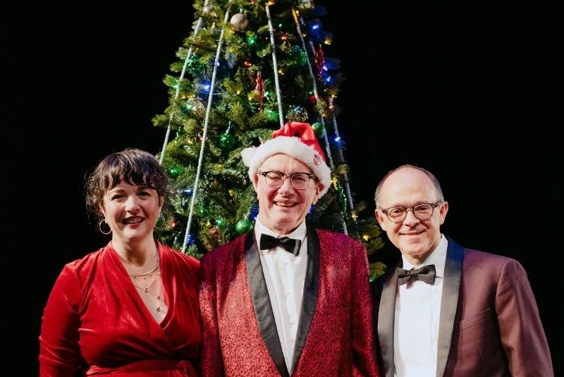 The people dressed in christmas colors in front of a christmas tree