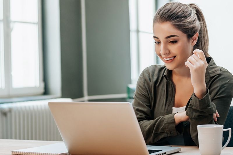 Undergraduate online student with a smile looking at her computer.