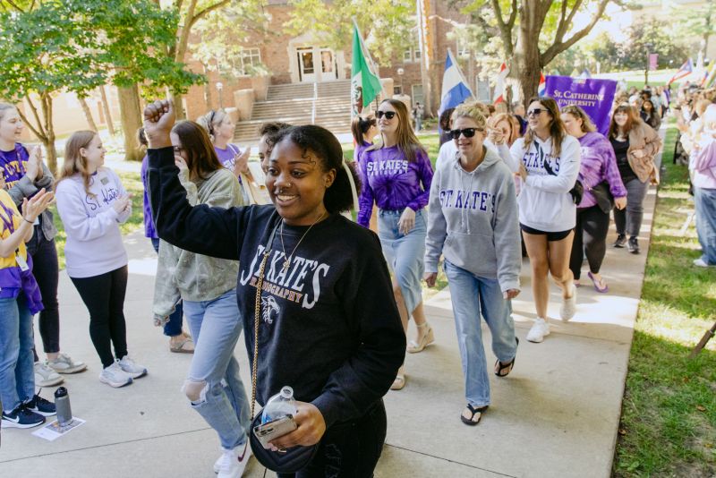Students smile and cheer as they process across campus.