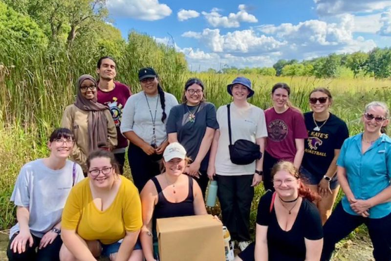 A group photo of Paula Furey, PhD, with her Algal Ecology class and Waḳaƞ Típi Awaƞyaƞkapi collaborative team outside.