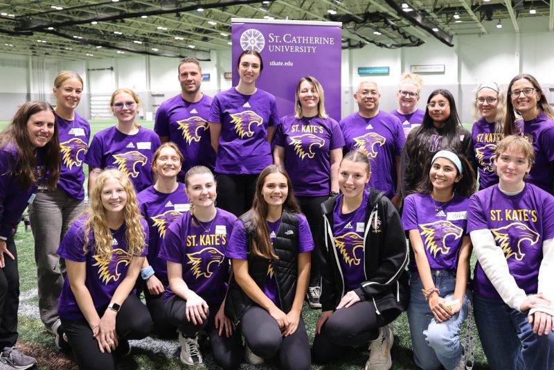 St. Kate's students, faculty, and staff pose inside a gym.
