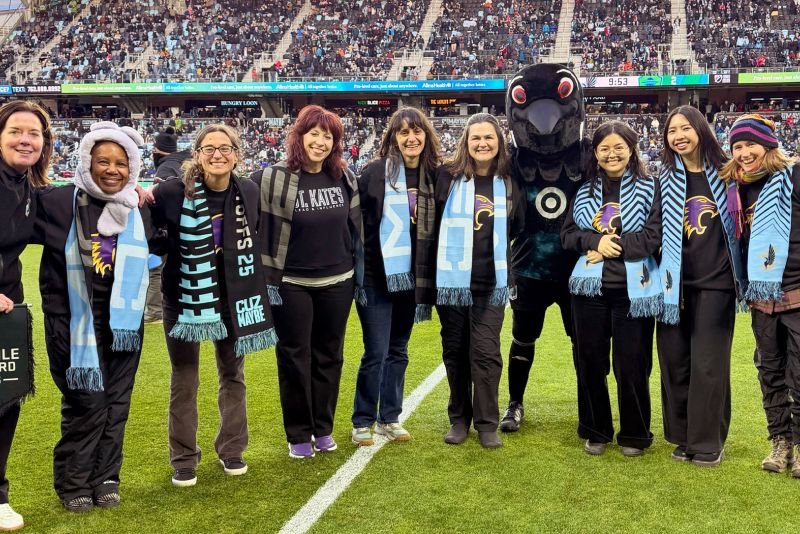 St. Kate's staff and students pose with the Loons mascot on the Minnesota United soccer field.
