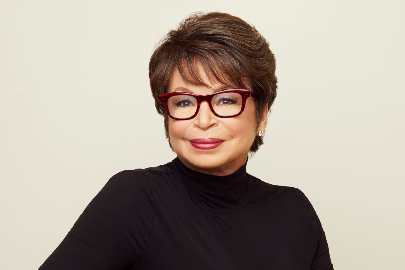 A woman wearing glasses and a black turtleneck smiles for a photo.