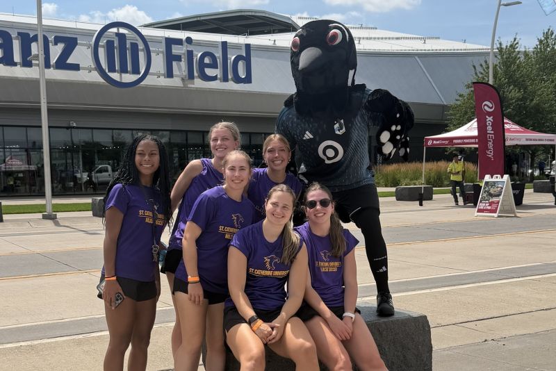 Wildcat soccer team members pose outside Allianz Field with the loon mascot