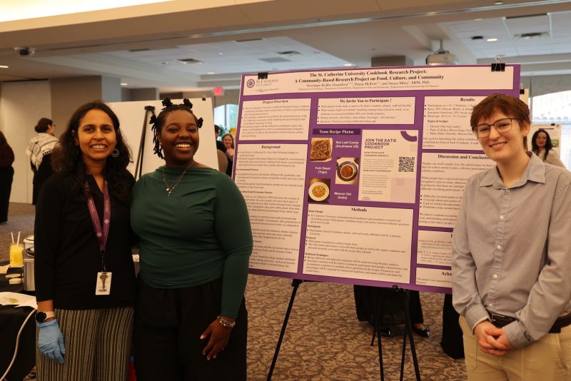 Two Summer Scholars students and a faculty mentor stand in front of a poster with their research.