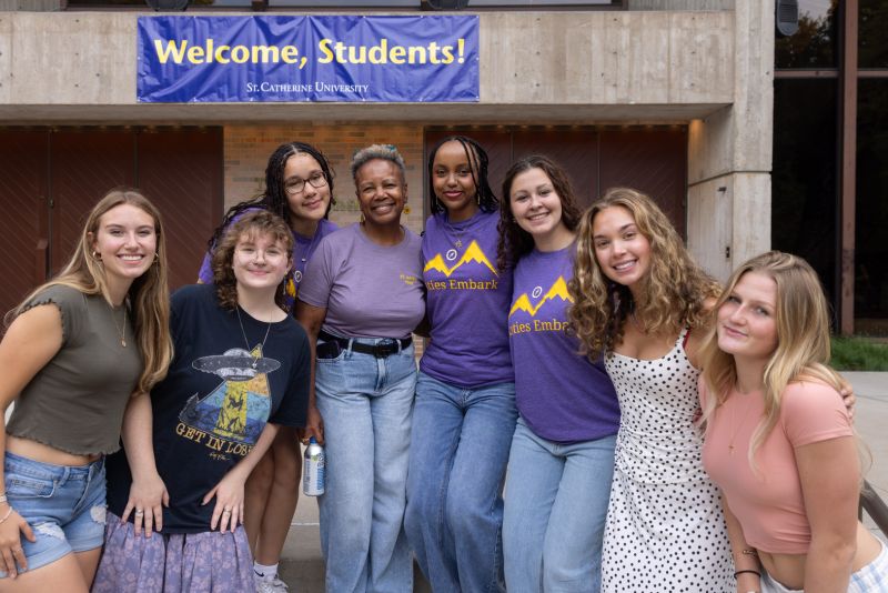President Evans poses with a group of students in front a sign that reads "Welcome, Students!"