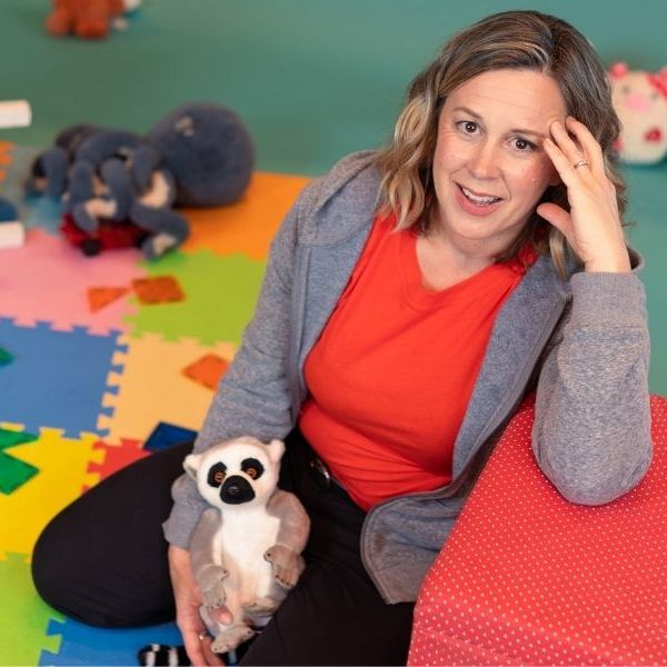 Woman sitting in a childrens playroom with her arm on a red block