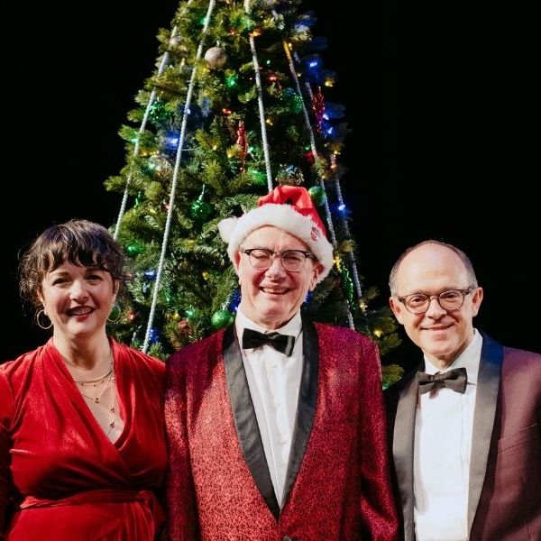 The people dressed in christmas colors in front of a christmas tree