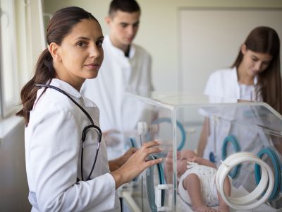 Neonatal Nurse examining baby in incubator with doctors