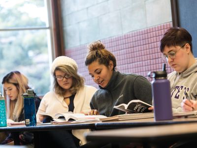 Four students sitting in a class following along in a reading