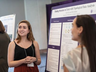 Two data science students presenting a poster board at an event