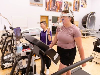 Female student doing test on exercise equipment with teacher