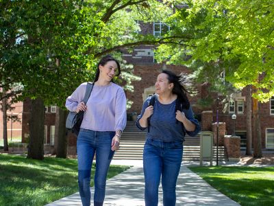 Two smiling students walking on campus.