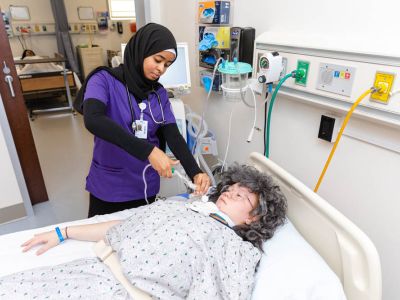 A Respiratory Care student practicing caring for a mannequin in a simulated medical environment.