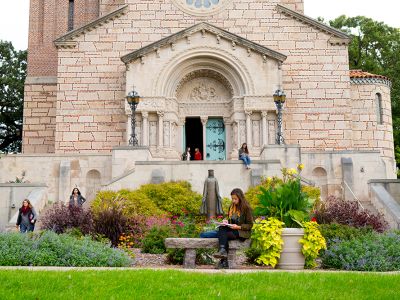 Our Lady of Vicotry Chapel. People are talking by the open door, and studying in the garden in front.