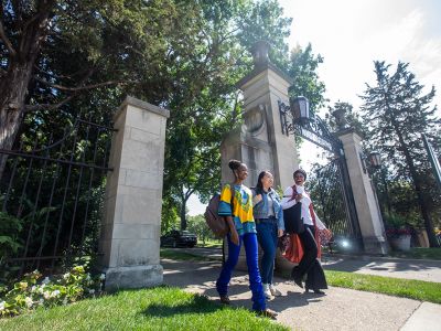 Thre BIPOC women students walking through the St. Catherine University gate.