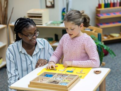 Student instructor sitting next to a table with a young child counting beads