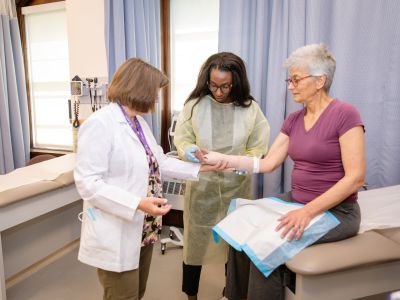 Patient receiving a cast on their wrist from a nursing instructor and student