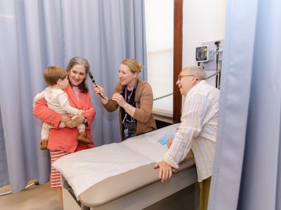 Nurse practitioner looking at a young patient who is being held in their parents arms