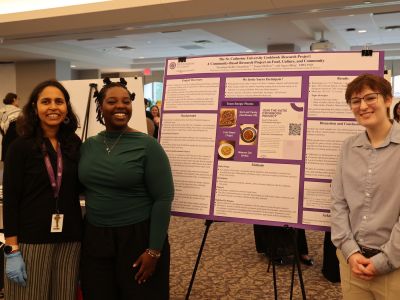 Two Summer Scholars students and a faculty mentor stand in front of a poster with their research.