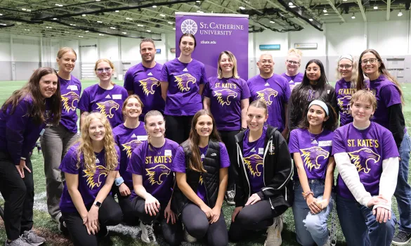 St. Kate's students, faculty, and staff pose inside a gym.