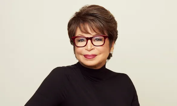 A woman wearing glasses and a black turtleneck smiles for a photo.
