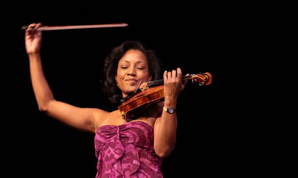 Close-up of Kelly Hall-Tompkins performing violin onstage in front of black background
