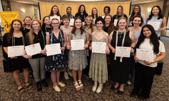 Phi Beta Kappa inductees stand holding their certificates. 