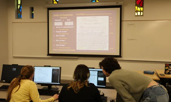 Students look over a laptop while doing research for a TRW class.