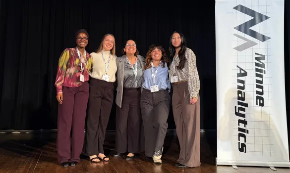 A group of four St. Kate's students and their supervisor gather on stage to celebrate a team win at the student data challenge by MinneAnalytics.