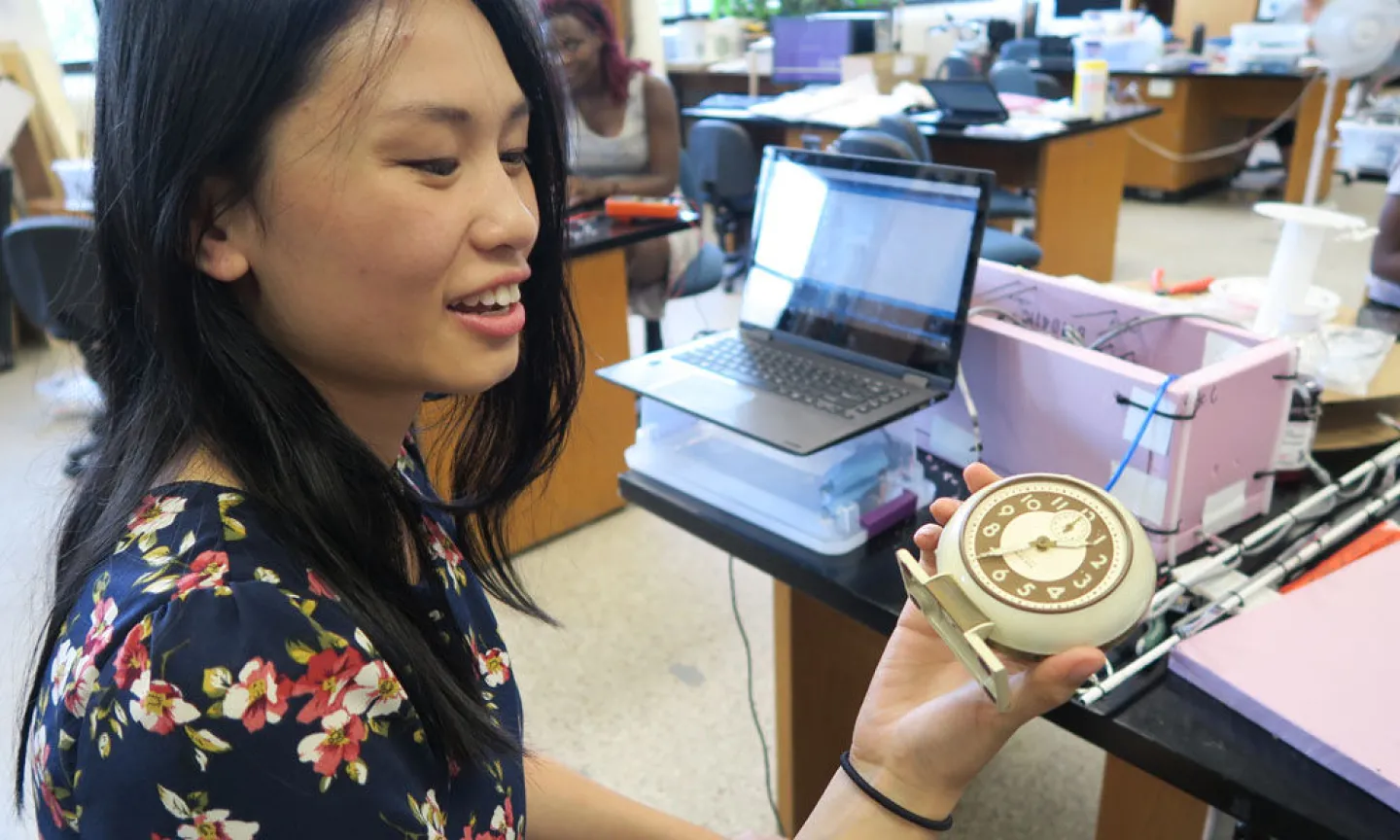 Summer Scholar Alynie Walter '18 displays "Grandma's Clock" (as nicknamed by the ballooning team), a clock from the 1920's that was painted with iridium to make the clock face glow in the dark and is slightly radioactive as a byproduct. The team uses "Grandma's Clock" to make sure that their radiation data-gathering equipment is working correctly. Photo by Michelle Mullowney '17